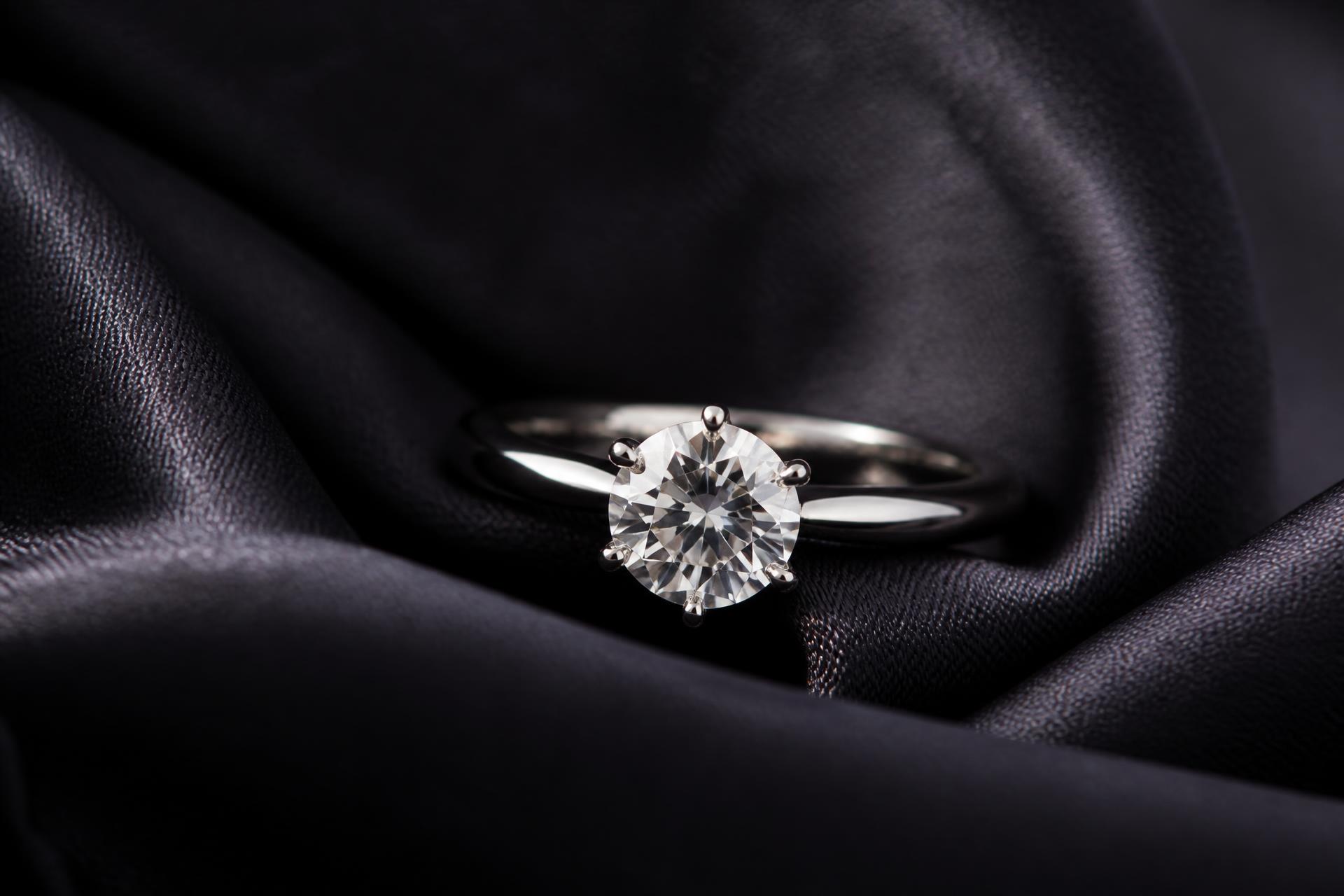 Diamond solitaire engagement ring on dark silk